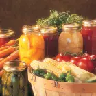 Canned food in jars and assorted raw vegetables.
