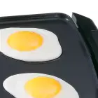 A close-up of the Cool-touch Griddle frying eggs.