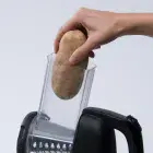 A close-up of a whole potato being put into the Professional SaladShooter&reg; electric slicer/shredder's food chamber.