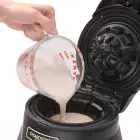 A close-up of batter being poured into the Belgian Waffle Bowl Maker.