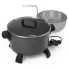 The Kitchen Kettle XL multi-cooker/steamer with the glass cover on the pot and the empty basket behind the multi-cooker.