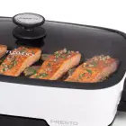 A close-up of the Presto Precise 16-inch Tuxedo digital precision skillet multi-cooker's glass cover with salmon cooking inside.