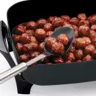 A close-up of the 12-inch Electric Skillet with a spoon resting in the spout.