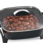 A close-up of the 12-inch Electric Skillet's glass cover with meatballs cooking in the pan.