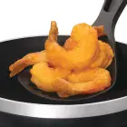 The deep fryer's scoop containing deep fried shrimp.