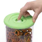 A finger pushing the button on the cover of a FreshDaddy Vacuum Container.