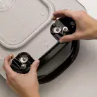 A close-up of a handle being removed from the 22-inch Electric Griddle.