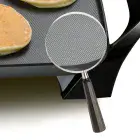 A close-up of a magnifying glass showing the textured nonstick surface of the 22-inch Electric Griddle.