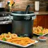 The FryDaddy® electric deep fryer on a kitchen counter. Plates of deep fried foods are around the fryer.