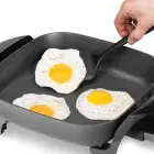 A close-up of a fried egg being removed from the 11-inch Electric Skillet.