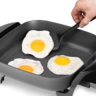 A close-up of a fried egg being removed from the 11-inch Electric Skillet.
