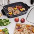 The 16-inch Electric Slimline Skillet on a kitchen counter as a pork chop is removed from the pan.