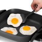 A close-up of a fried egg being removed from the 11-inch Electric Skillet.