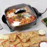 The 12-inch Electric Skillet on a kitchen counter with food cooking in the pan.