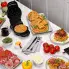 An overhead view of the Flip Belgian Waffle Maker on a kitchen counter. The cover is open and a baked waffle is on the cooking grid. Other baked waffles and toppings are also shown.
