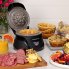 The Belgian Waffle Bowl Maker on a kitchen counter with the cover open and a waffle bowl on the cooking grid. Other waffle bowls and stuffing ingredients are also shown.