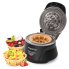 The Belgian Waffle Bowl Maker with the cover open and a waffle bowl on the cooking grid. Two filled waffle bowls are to the left of the unit.
