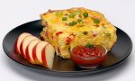 A serving of hash brown breakfast casserole with apple slices on a plate.