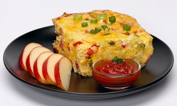 A serving of hash brown breakfast casserole with apple slices on a plate.