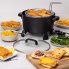 The Kitchen Kettle XL multi-cooker/steamer on a kitchen counter with fried fish in the basket. Several other foods are around the multi-cooker.