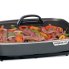 Steak and peppers cooking in the 16-inch Electric Slimline Skillet with the cover on.
