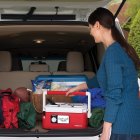 Woman putting the slow cooker in the back of an SUV.