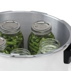 A close-up of the top of the Presto Precise 23-Quart Digital Pressure Canner with the cover off and jars of food in the canner.