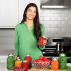 A woman in a kitchen with jars of canned foods.